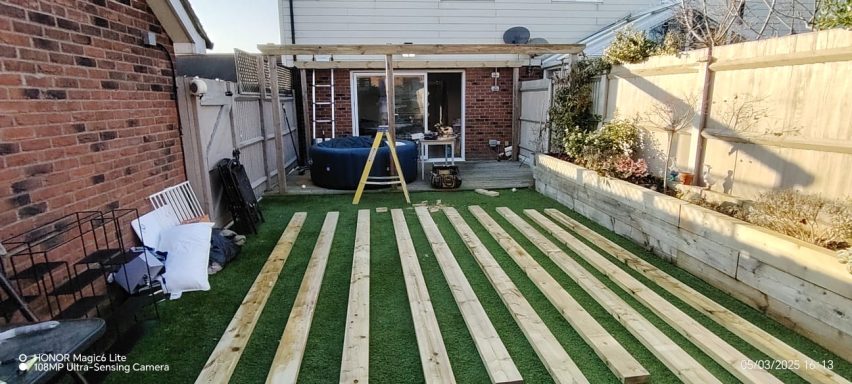 Wooden planks arranged on grass in a garden under construction.