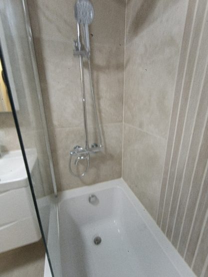 Modern bathtub with a showerhead in a tiled bathroom setting.