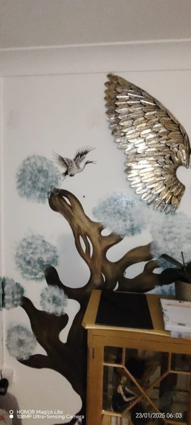 Decorative wall mural with a tree design and metallic bird sculptures.